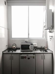 cocina con microondas y fregadero y ventana en Monoambiente en el centro de Recoleta en Buenos Aires