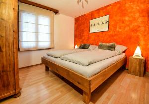 a bedroom with a bed with an orange wall at Casa al Lag - direkt am Laaxersee in Laax +44 photos