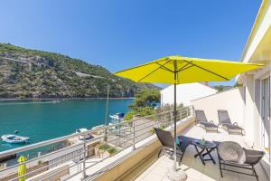 a balcony with a yellow umbrella and chairs and the water at Villa Casia in Mokošica