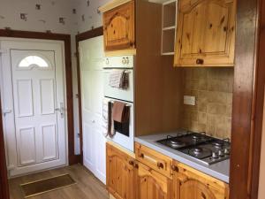 a kitchen with wooden cabinets and a stove top oven at 3 Bedroom Culduthel House Free Parking in Inverness
