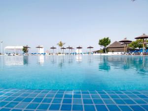a swimming pool with blue water and umbrellas at Sandos Papagayo in Playa Blanca