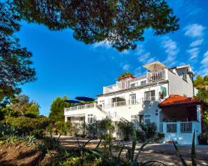 a white house with trees in the foreground at Apartments Velo Lago in Lastovo