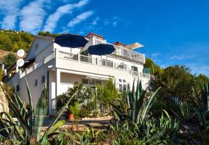 een wit gebouw met paraplu's ervoor bij Apartments Velo Lago in Lastovo