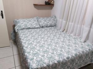 a bed with a flowered blanket and a window at Apartamento Meia Praia - 140 metros do mar in Itapema