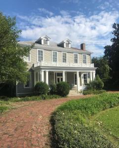 a large white house with a brick driveway at Clark House Inn in Clarksdale