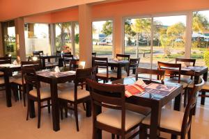 un restaurante con mesas y sillas de madera y ventanas en Brisas del Lago Apart y Hotel en Federación