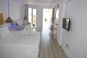 ein weißes Wohnzimmer mit 2 Betten und einem TV in der Unterkunft Ocean Dreams Suites in Ayia Napa