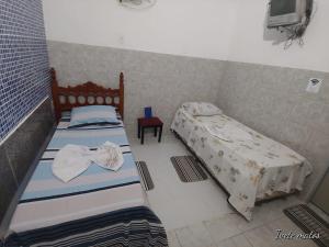 een slaapkamer met 2 bedden en een stoel bij Pousada Refúgio in João Pessoa