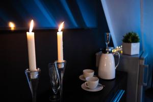 a table with two candles and two glasses and cups at Apartment Charlie in Prague