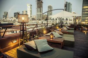 a balcony with couches and tables and a city skyline at Brown TLV Urban Hotel a member of Brown Hotels in Tel Aviv