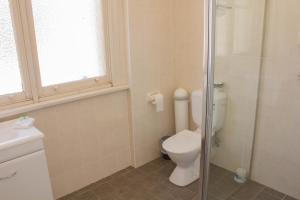 a bathroom with a toilet and a glass shower at Gardners Inn Hotel in Blackheath