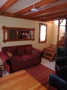 sala de estar con sofá rojo y TV en Cabaña Centrica, en Coyhaique