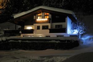 dom oświetlony śniegiem w nocy w obiekcie Haus Fischer w mieście Pettneu am Arlberg