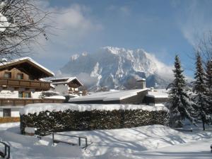 a snow covered mountain in front of a house at Haus Arnika in Lermoos