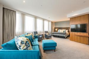 a living room with a blue couch and a bedroom at Distinction Christchurch Hotel in Christchurch