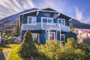 ein blaues Haus mit einem weißen Balkon darüber in der Unterkunft Arctic Paradise B&B in Seward