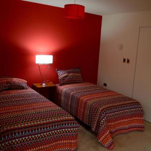 two beds in a room with a red wall at Vía Lavalle Suites in San Luis