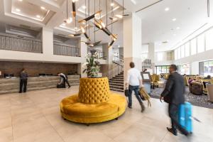 a lobby with a yellow chair and people walking in the lobby at Distinction Christchurch Hotel in Christchurch