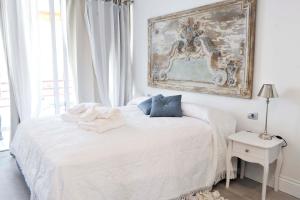 een slaapkamer met een wit bed en een schilderij aan de muur bij Sweet home deluxe in Playa de las Americas