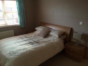 a bedroom with a bed with white sheets and a window at Portstewart - holiday let in Portstewart
