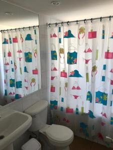 a bathroom with a toilet and a shower curtain at Departamento en Papudo in Papudo