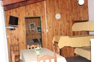 una habitación con mesa y sillas y una habitación con paredes de madera en Villa Leandro en Mina Clavero