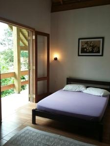 1 dormitorio con 1 cama y puerta corredera de cristal en Casa de Lenir, en Garopaba