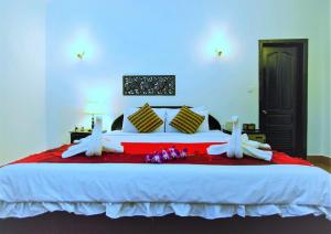 a bedroom with a large bed with white sheets and flowers at Sonalong Boutique Village & Resort in Siem Reap