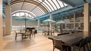 un comedor con mesas, sillas y sombrillas en Albany Airport Inn, en Albany