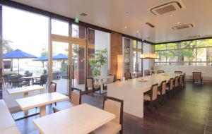 um restaurante com mesas, cadeiras e janelas em K's Street Hotel Miyazaki em Miyazaki