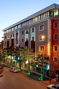 a building with palm trees in front of a street at Balturk Hotel Sakarya in Sakarya