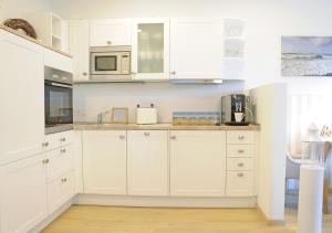 eine Küche mit weißen Schränken und einer Mikrowelle in der Unterkunft Ferienwohnung KNUT am Hafen in Heiligenhafen