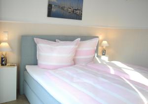 1 dormitorio con 1 cama con almohadas rosas y blancas en Ferienwohnung KNUT am Hafen en Heiligenhafen