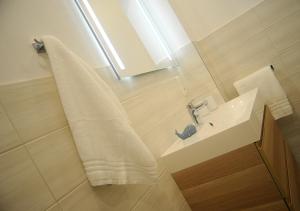 ein weißes Badezimmer mit einem Waschbecken und einem Spiegel in der Unterkunft Ferienwohnung KNUT am Hafen in Heiligenhafen