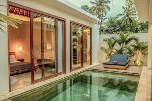 a house with a swimming pool and a bedroom at Kumbara Villas in Kuta Lombok