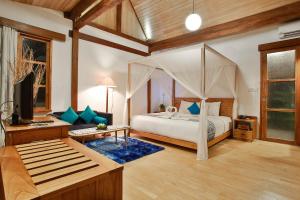 ein Schlafzimmer mit einem Himmelbett und ein Wohnzimmer in der Unterkunft Villa So Long Banyuwangi - Ijen in Banyuwangi