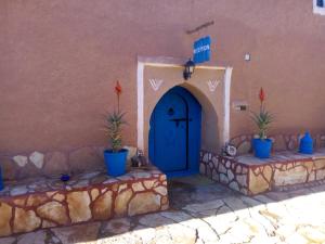 a blue door in a building with two potted plants at Dar Mouna La Source in Aït Benhaddou
