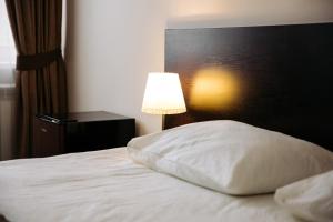a bed with a white pillow next to a lamp at West Hotel in Smolensk