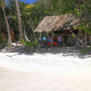 Turtle Dive Homestay في Kri: مجموعة من الناس تقف في كوخ على الشاطئ