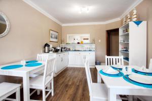 a kitchen and dining room with white tables and chairs at The Reef Apartments in East London