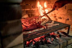 a person cooking sausages and sausage on a grill at Villaggio Passo Dell'Arciprete in Vieste
