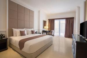 a hotel room with a large bed and a television at Grand Palace Hotel Sanur - Bali in Sanur