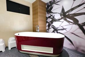 una vasca rossa in un bagno con una pianta di HOTEL 小粋 -coiki- a Hiroshima