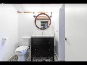 uma casa de banho com um WC, um lavatório e um espelho. em WeRentVLC - Encantador Loft Casco Antiguo em Valência