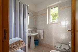 a bathroom with a sink and a toilet and a window at Villaggio Passo Dell'Arciprete in Vieste