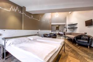 a bedroom with a large white bed and chairs at Sophie's Hostel in Prague