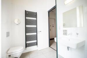 a white bathroom with a toilet and a sink at Sophie's Hostel in Prague
