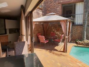 um pátio com uma mesa e um guarda-sol ao lado de uma piscina em Fa'Trez Guest House & Spa em Pretoria