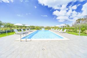 a swimming pool with white chairs and umbrellas at Case Vacanze Mare Nostrum - Villas in front of the Beach with Pool in Campofelice di Roccella