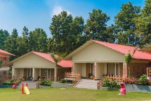 dos casas con techos rosas y un niño de pie delante en Kushal Palli Resorts- A unit of PearlTree Hotels & Resorts, en Purulia